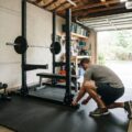 Mand bygger fitnessrum hjemme i garagen med gulvmåtter og vægte